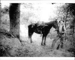 Hamilton Otis standing with a rifle with his horse, Cazadero, California, about 1900