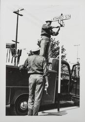 City workers putting up a street sign at Third and E Streets