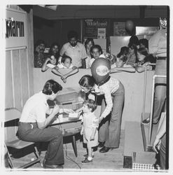 Bank of Marin representative reading a winning number on a raffle ticket in the Bank of Marin booth at the Sonoma-Marin Fair, Petaluma, California, 1978