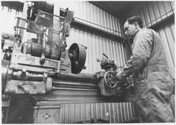 Metal lathe operator working in an unidentified machine shop, 1950s or 1960s