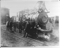 Railroad crew next to locomotive decorated for a Fourth of July celebration