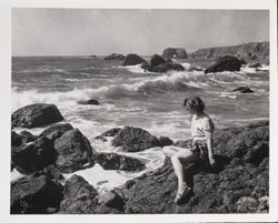 Woman sitting on the rocks admiring the waves