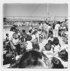 Bank of Marin goat milking team with their goats and supporters in Bank of Marin T-shirts watching a rodeo on Farmers' Day at the Sonoma-Marin Fair, Petaluma, California, 1978