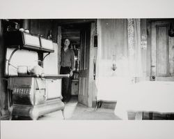 Kitchen interior of the rural home of Edward L. Anderson, also known as, Edward Burghgren, with Edward in the doorway, Petaluma, California, January 25, 1936