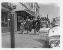 Cecilia Payne and models for the "Dramatic Moods" fashion show walk on the sidewalk outside the Topaz Room, Santa Rosa, California, 1959