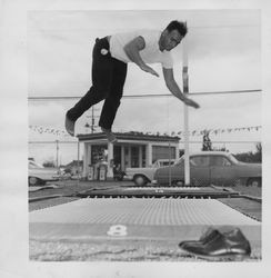 Man jumping on a trampoline on the northwest corner of East Washington and Wilson, Petaluma, California, 1962