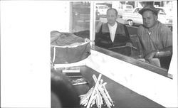 Leonard Forman and Mr. Fishman look into Mattei Brothers, Petaluma, California, during window judging, 1962