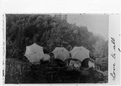 People sitting on a rock holding umbrellas