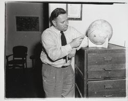 Leonard J. Karsevar scans a world globe