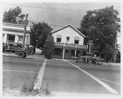 Road construction equipment on an unidentified city street, likely in Santa Rosa, California, with a mix of residences and commercial buildings, 1950s