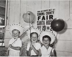 Three smiling little girls holding balloons at the Sonoma County Fair, Santa Rosa, California, 1957