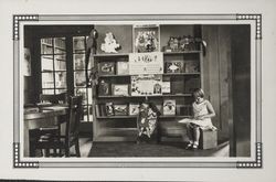 Girl reading a book beside the display area in the Carnegie Library children's room