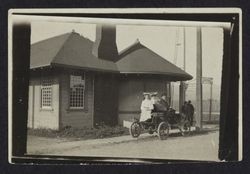 Unidentified train station with a family in a car waiting for the train