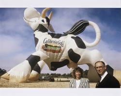 Al Bono and Dawn Roe of the California Cooperative Creamery stand with their backs to a hot air balloon shaped like a cow--advertising California Gold Dairy Products--at the 1994 Sonoma County Hot Air Balloon Classic, July 1994