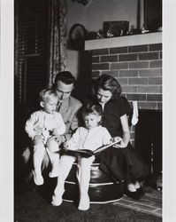 Alwes family reading a book together in front of a fireplace, Santa Rosa, California, Christmas, 1949