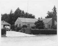 Stuccoed, single-story house with an Ford coupe sitting outside the detached garage in an unidentified Sonoma County, California, location, late 1940s or 1950s