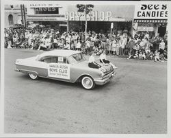 Car with two girls on hood preceeding the Santa Rosa Boys Club Junior Drill Team