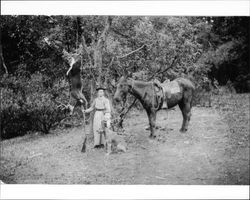 Flora Otis and a child pose beside a dead deer, Cazadero, California, about 1900