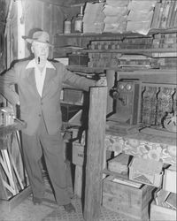 Unidentified man standing in front of shelves of old ledgers, Petaluma, California, 1953