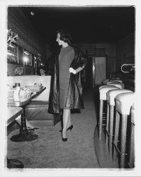 Model in evening dress and a long coat in the "Dramatic Moods" fashion show in the Topaz Room, Santa Rosa, California, 1959