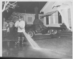 Petaluma Fire Department firefighters hose down sidewalk in front of 906 Western Avenue, Petaluma, California after Harry Gene Warner of Spenard, Alaska, crashed his Dodge Charger into the porch, February 11, 1965