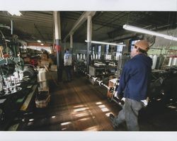 Tim Rhodes and Russell Strickland moving drive shaft from braiding machines at Sunset Line & Twine Company in Petaluma, California, Dec. 2006