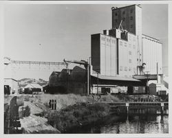 View of the Nulaid Foods Inc. feed mill, the Petaluma River and railroad box cars