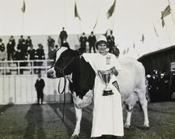 Lily Ramatici stands with the winning milk cow and her loving cup at the Panama Pacific International Exposition world's fair, 1915