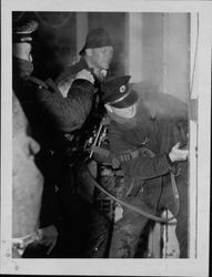 Petaluma Fire Department firefighters breaking the lock on a door at an unidentified commercial structure fire, 1950s