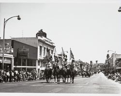 Petaluma Riding and Driving Club color guard precedes its club members in the Sonoma-Marin Fair parade in Petaluma, California, 1950s