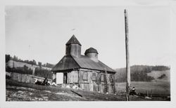 Men lounging on the ground outside the Chapel at Fort Ross