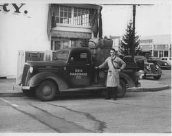 Unidentified man standing in front of Rex Hardware Co. truck parked in front of Schindler's Bakery at the corner of B and Main Streets, Petaluma, California, about 1938