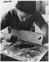 Sculptor working on a bas-relief image of a duck in flight, 1970s