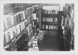 Book stacked on the floor in front of shelving in the crumbling Santa Rosa, California Carnegie Library, 1960