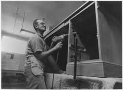 Furniture maker drilling a hole in a desk case, 1950s or 1960s