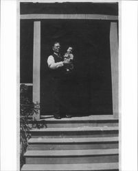 James J. Medley standing in the doorway of his home at 231 Wilson Street, Petaluma, California with his son Lincoln "Neil" Medley in his arms, about 1919