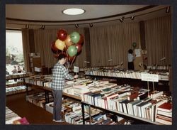 Library Director David Sabsay holding balloons at the Friends of the Library Spring Book Faire in the Forum room of the Central Library, Santa Rosa, California, 1972