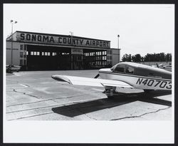 Cherokee Cruiser plane in front of the main hanger at the Sonoma County Aiport, 1973