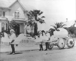 Boys dressed as chickens pulling an egg float in front of Fritsch home