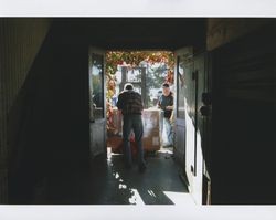 Big Dennis Henderson outside by a forklift with a co-worker who is using a pallet jack to move a box at Sunset Line & Twine Company in Petaluma, California, Dec. 2006