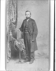 Portrait of an unidentified Petaluma, California, bearded man with his hand resting on a large book, 1860s or 1870s