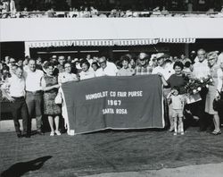 Fair officials and racetrack enthusiasts holding Humboldt Co. Fair Purse banner at the Sonoma County Fair Racetrack, Santa Rosa, California