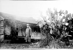 Unidentified man in front of the first house built by Elisha Ely