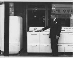 Rex Hardware salesman, George Dickerson standing front of a stove outside the store at 3-5 Main Street, Petaluma, California, about 1938