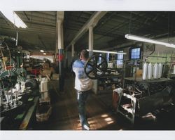 Russell Strickland carrying a wheel from a braider machine on the first floor of the Sunset Line & Twine Company building in Petaluma, California, Dec. 2006