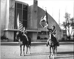 Two members of the color Guard of the California Centaurs mounted junior drill team in front of the Exhibit Building at the Sonoma County Fairgrounds in Santa Rosa, California, 1947