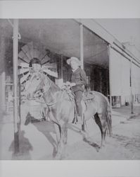 Boy associated with the Akers family and identified as Rudolf T. sides astride a horse in front of a store, possibly in Sonoma, California, about 1900