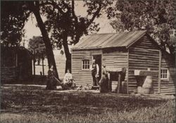 Early settlers outside their small wooden house