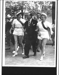 Adlai Stevenson campaigning in Walnut Park, Petaluma, California, 1952, accompanied by two women dressed as chickens