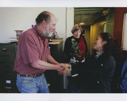 John Agnew shaking hands with an unidentified employee with manager Mary Graham standing nearby at at the farewell party at Sunset Line & Twine Company in Petaluma, California, on Dec. 22, 2006